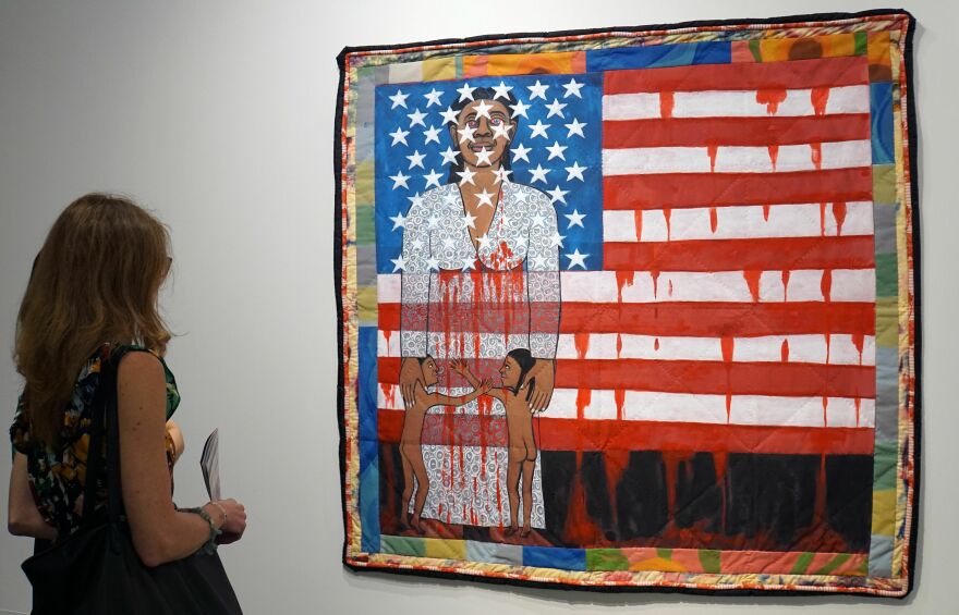 A visitor watches the work of artist Faith Ringgold, "The Flag is Bleeding #2" during a preview on December 4, 2019.