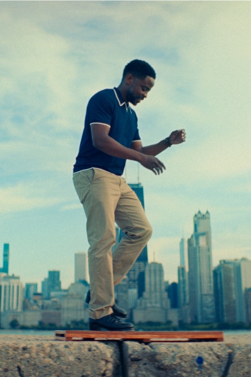 A person tap dances on a piece of wood with the Chicago skyline in the background