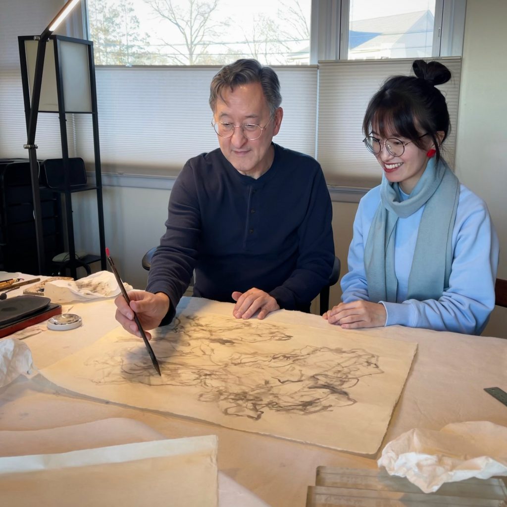 The artist and curator of the exhibition at Fu Qiumeng Fine Art, looking at an ink painting.