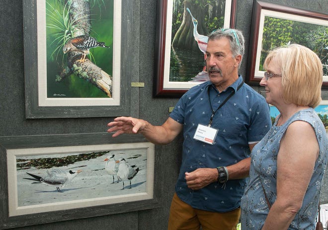Lakeland artist Stephen Koury speaks with Lori Folk of Lakeland in Koury's nature and wildlife art work booth during the Mayfaire by-the Lake in Lakeland in 2021.