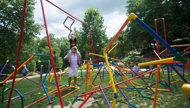 Derek Watson of Simpsonville lifts his son Ries, 12, on his shoulders to add a piece to a community sculpture during Artisphere in downtown Greenville on Friday, May 13, 2016.