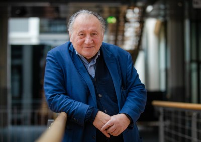 Portrait of Peter Weibel leaning over a balcony and smiling.