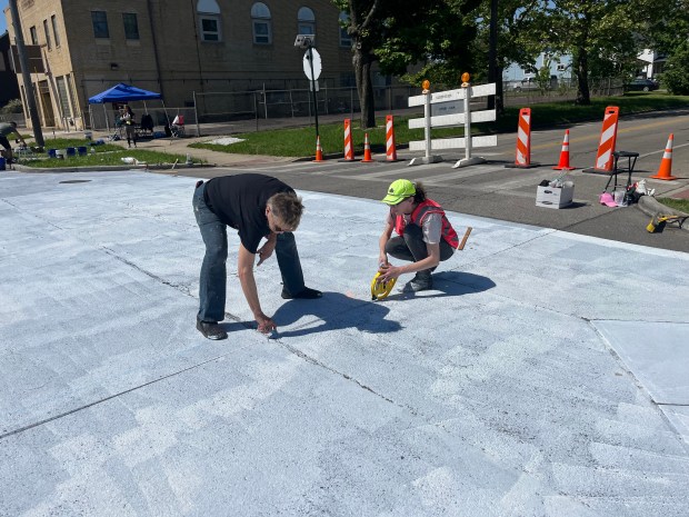 FireFish Arts Artistic and Funding Director Joan Perch and Lorain engineering intern Gwen Frey measure out a grid for the city's new mural on E 31st St. and Pearl Ave. (Martin McConnell -- The Morning Journal)