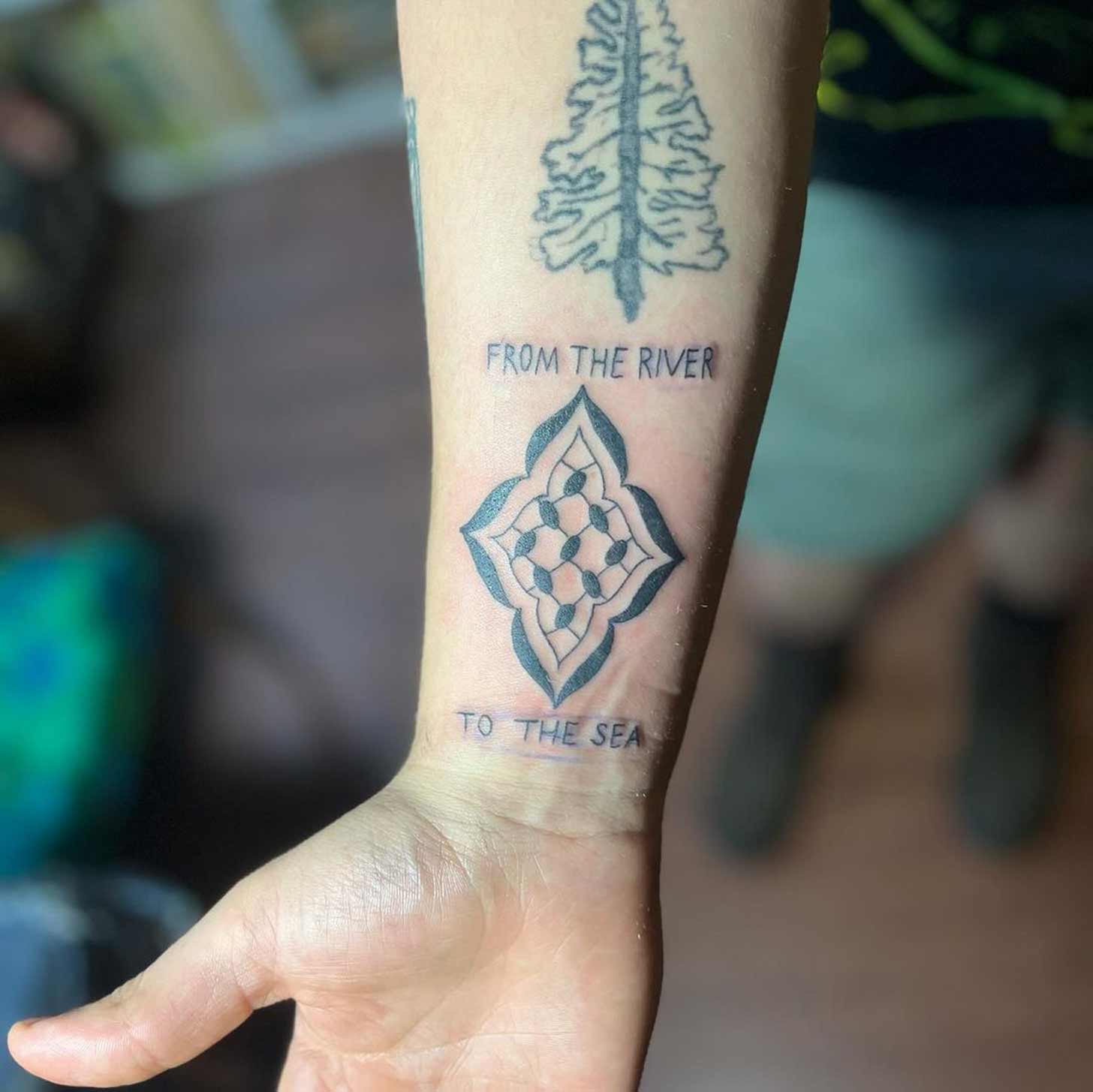 A tattoo that reads "from the river to the sea" with keffiyeh stitching done in support of the Hibr tattoo fundraiser 