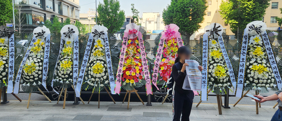Wreaths of flowers displaying boy band BTS's fans' messages of disapproval with BigHit Music, the band's label, and its parent company HYBE's management are displayed in front of HYBE's headquarters in Yongsan District, central Seoul, on May 3. [YONHAP]