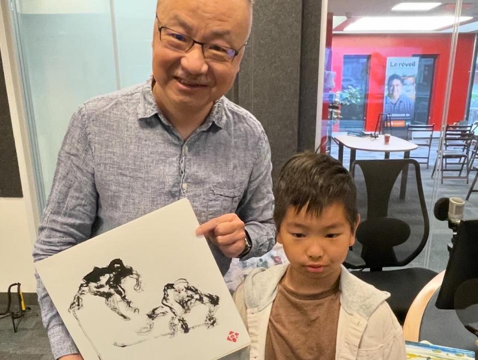 Xin and Yilang Liu pose with one of Xin's paintings on a recent interview at the CBC News studio in Charlottetown. Xin was inspired by watching Yilang play hockey.