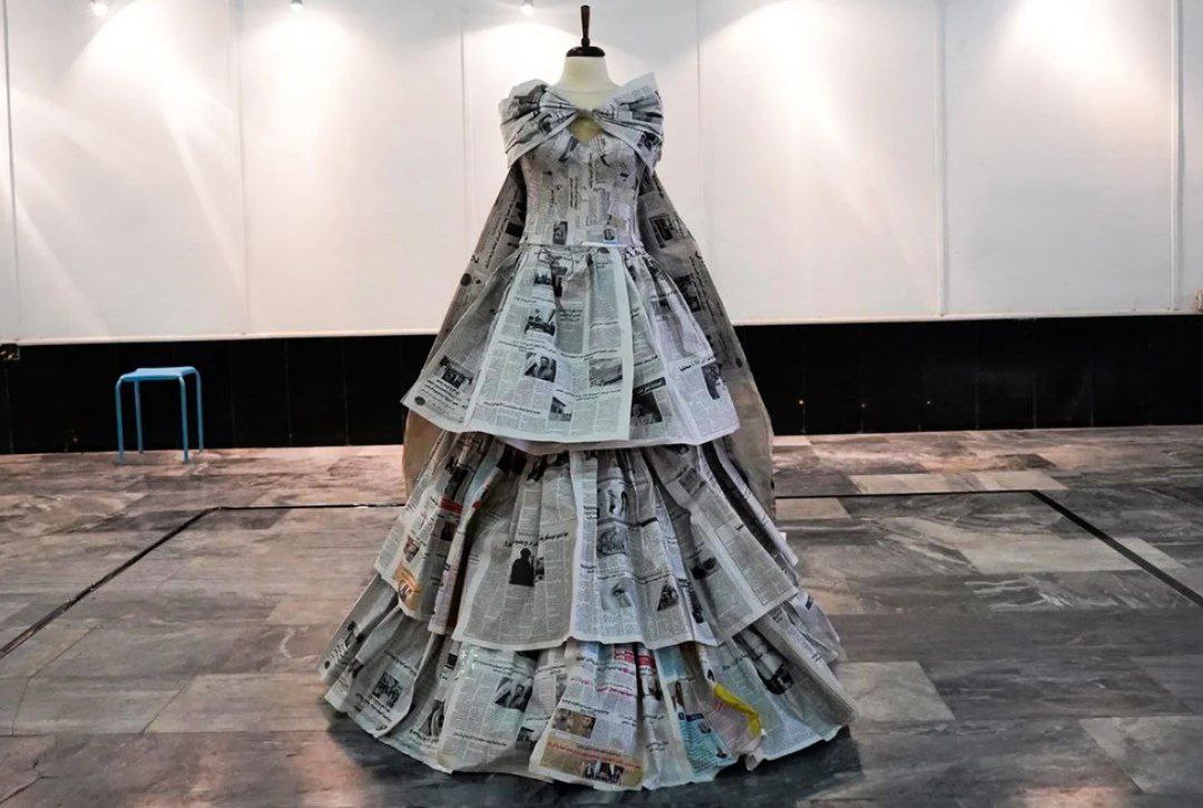 A woman wearing a wedding dress made of newspapers