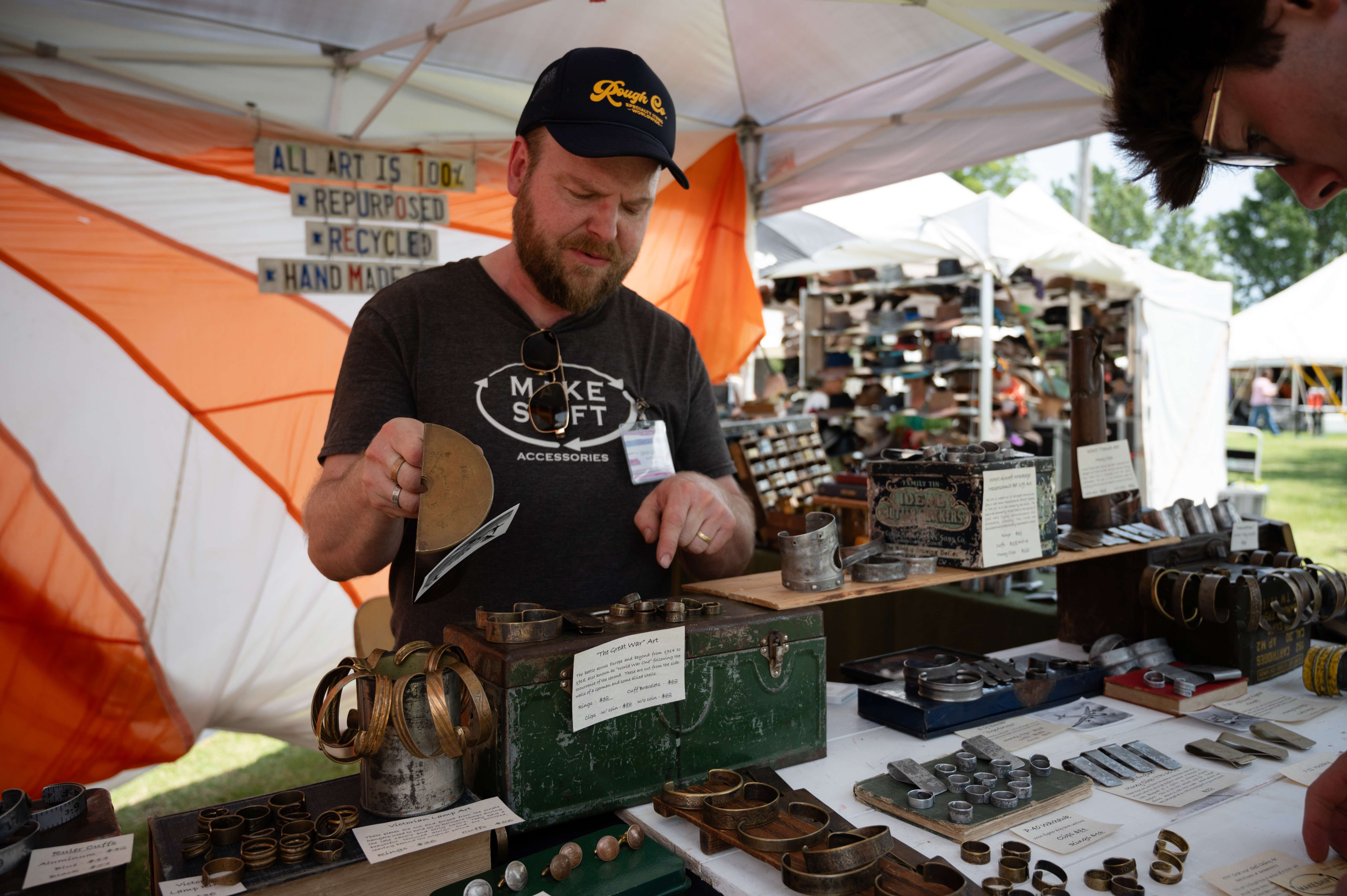 Devin Johnson, owner of Makeshift Accessories from Northfield, Minn., chats with a customer, Peyton Ott from Kansas City, during the Smoky Hill River Festival on Friday, June 14, in Oakdale Park in Salina. <b>Photo by Olivia Bergmeier</b>