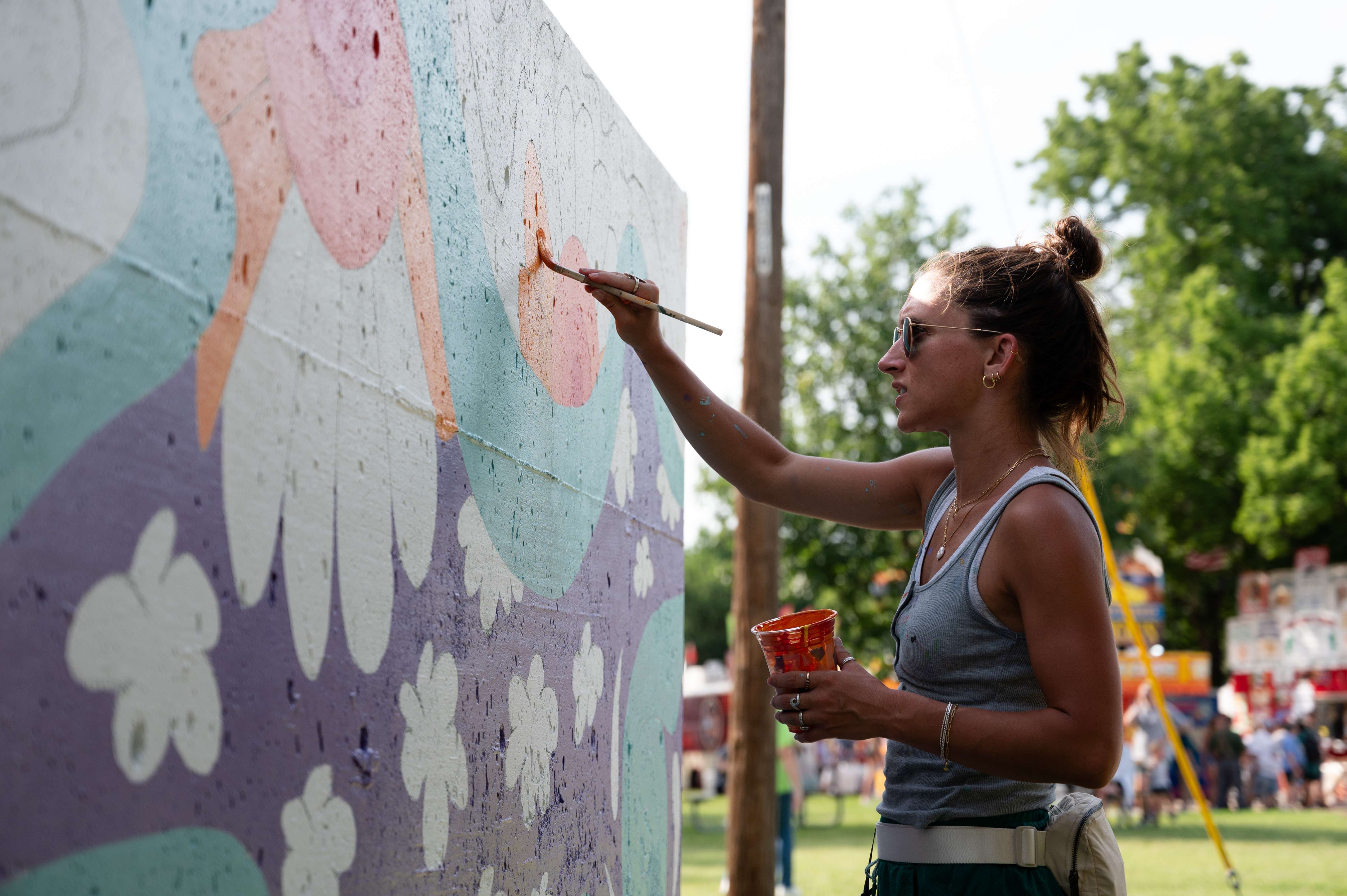 Katie Brown paints the bathrooms near the entrance to Oakdale Park as one of the performing artists during the Smoky Hill River Festival on Friday, June 14. <b>Photo by Olivia Bergmeier</b>