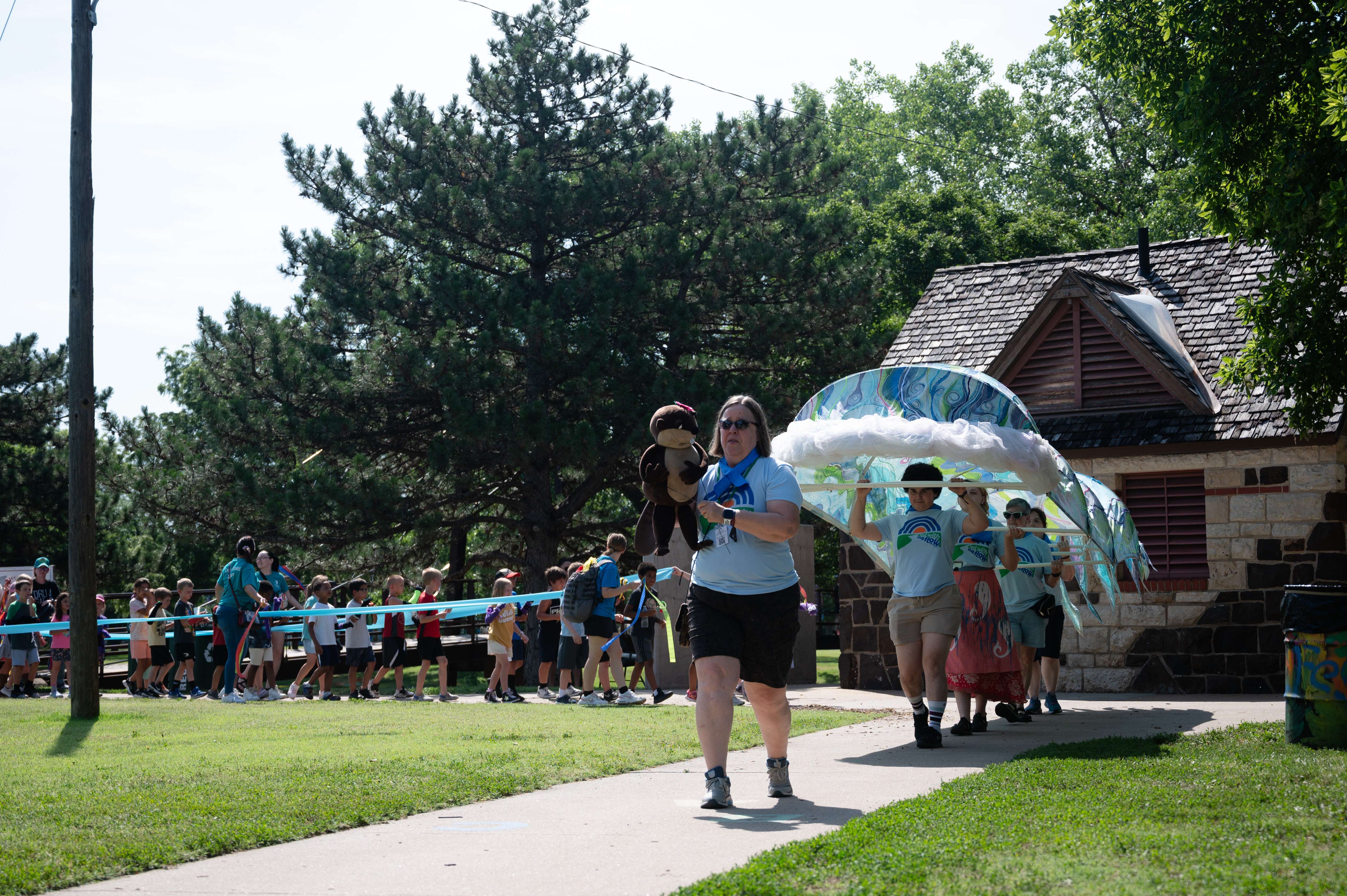 Friends of the River Foundation Executive Director Jane Anderson and her puppet pal Bella Beaver lead YMCA kids through Oakdale Park during the 2024 Smoky Hill River Festival on Friday, June 14. <b>Photo by Olivia Bergmeier</b>