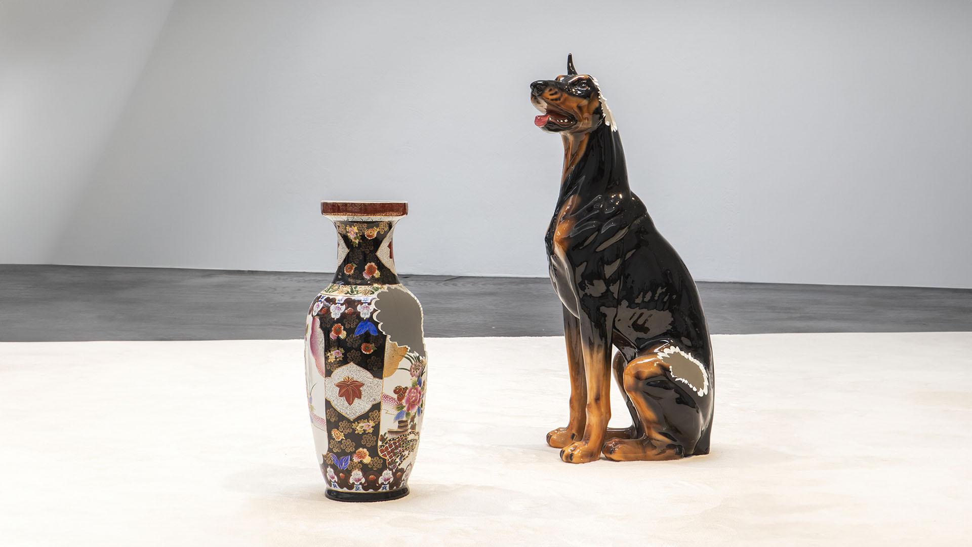 A porcelain statue of a doberman next to an oriental vase