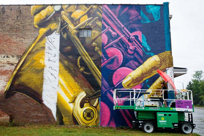 Cameron Moberg of San Fransisco watches the sky for rain while spray painting a mural on the side the Monarch Building at 519 South Michigan Street during Mural Mania on Friday, July 5, 2024, in South Bend. This year marks South Bend's third Mural Mania where artists from around the world paint murals across the city at the same time.