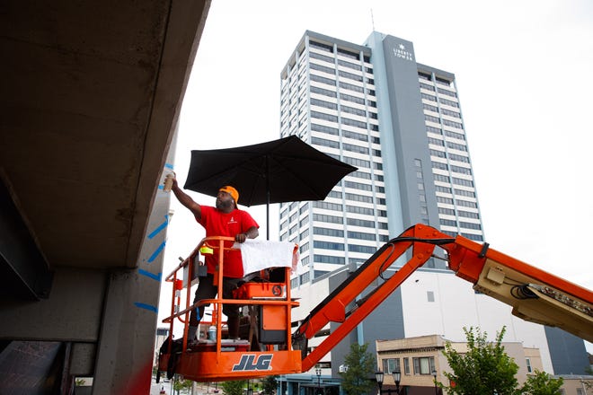 Max Sansing spray paints the side of the Main & Colfax garage during Mural Mania on Friday, July 5, 2024, in South Bend. This year marks South Bend's third Mural Mania where artists from around the world paint murals across the city at the same time.