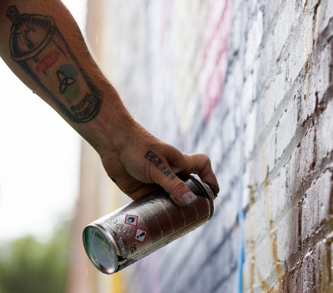 Cameron Moberg of San Francisco spray paints a mural on the side the Monarch Building at 519 S. Michigan St. during Mural Mania on Friday, July 5, 2024, in South Bend. This year marks South Bend's third Mural Mania where artists from around the world paint murals across the city at the same time.