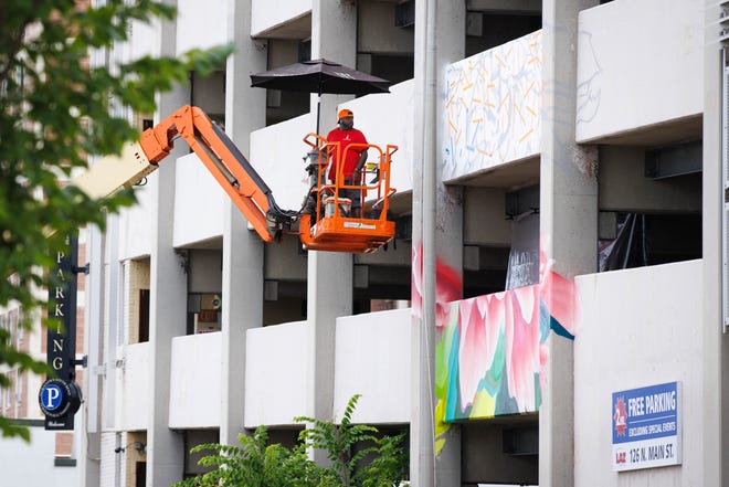 Max Sansing moves his crane closer to spray paint the side of the Main & Colfax garage during Mural Mania on Friday, July 5, 2024, in South Bend. This year marks South Bend's third Mural Mania where artists from around the world paint murals across the city at the same time.