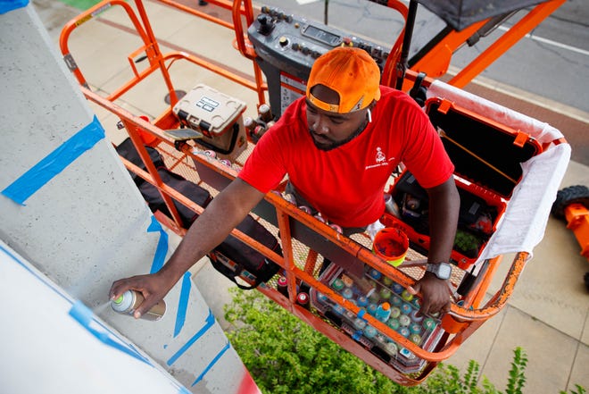 Max Sansing spray paints the side of the Main & Colfax garage during Mural Mania on Friday, July 5, 2024, in South Bend. This year marks South Bend's third Mural Mania where artists from around the world paint murals across the city at the same time.