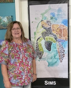 Sharon Sims stands beside her banner, Watercolor Turtle.