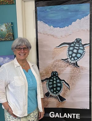 Cynthia Galante stands beside her banner, Baby Turtles.