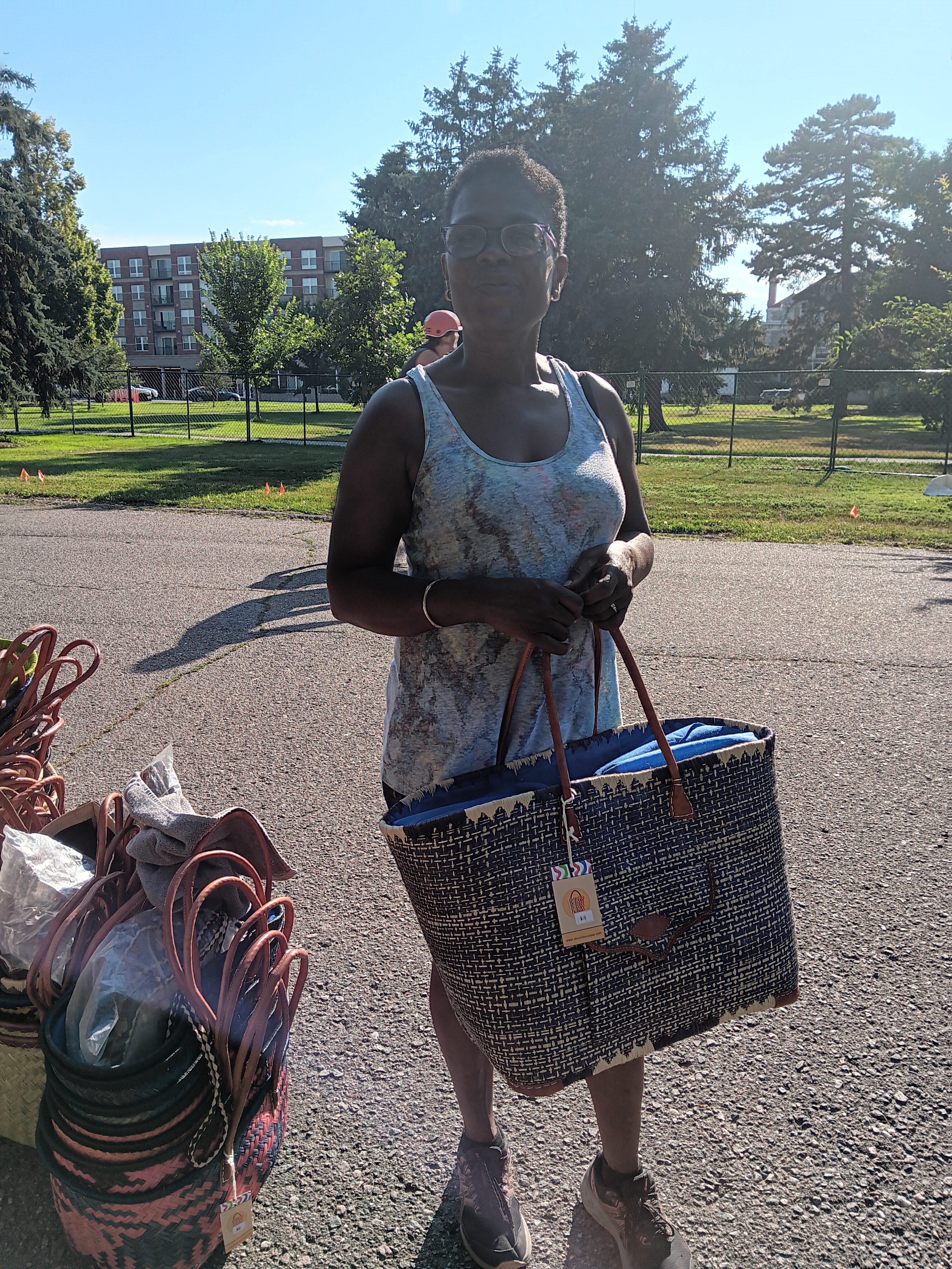 A woman stands holding a bag that she is selling.