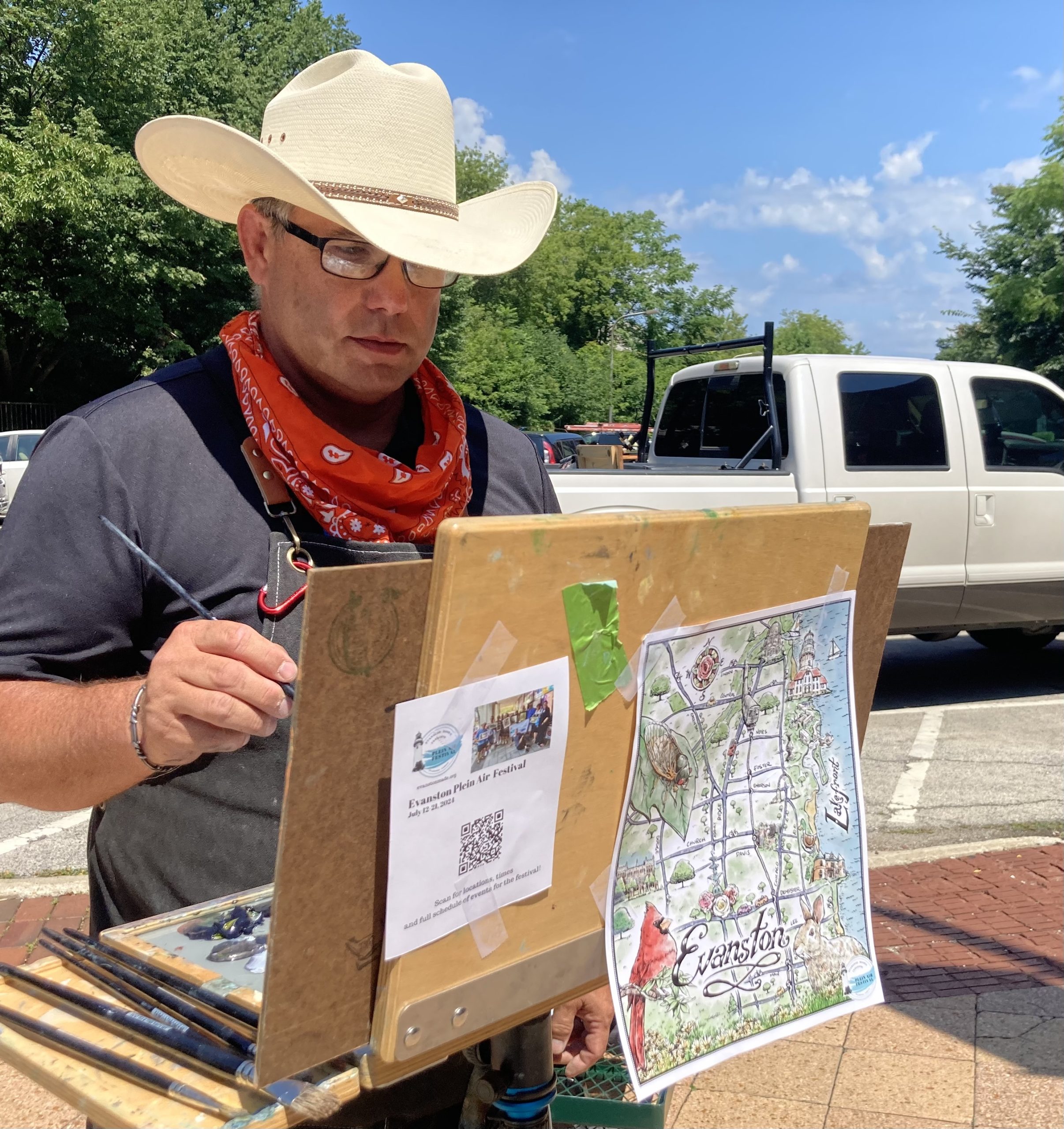 man in cowboy hat painting outdoors