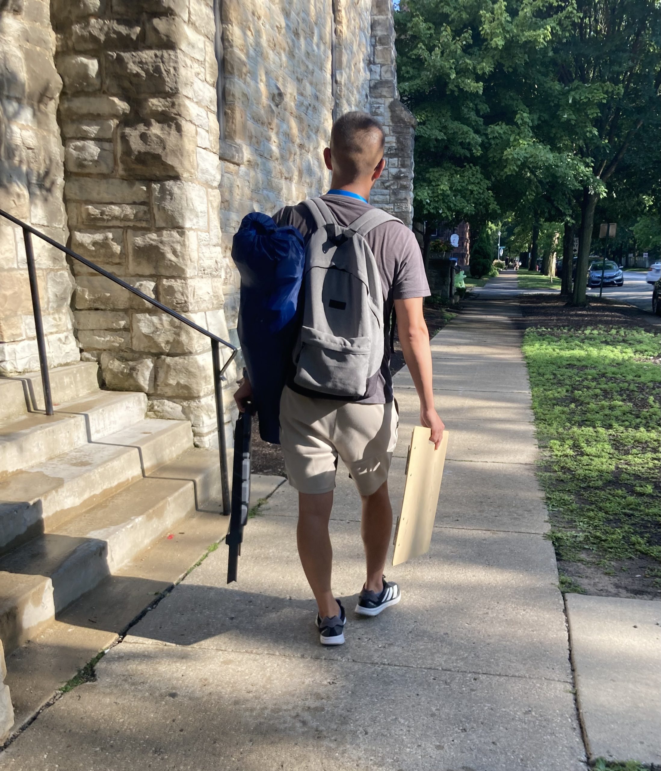 young man walking away carrying art supplies