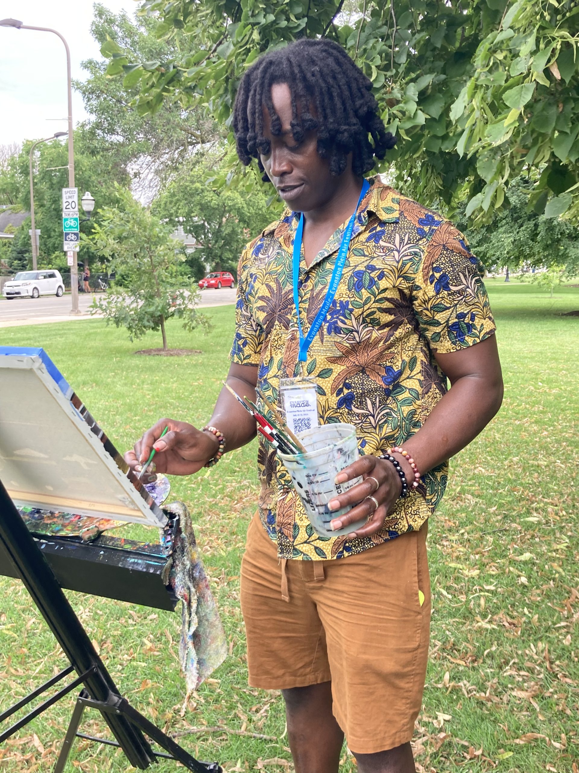 young, Black man standing to paint in outdoor setting