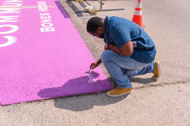 Deandre Jones a local artist signs his creative crosswalk design Tuesday at Bones Hooks Park in Amarillo.