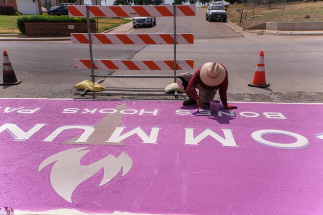 A worker finishes up on a creative crosswalk Tuesday at Bones Hooks Park in Amarillo.