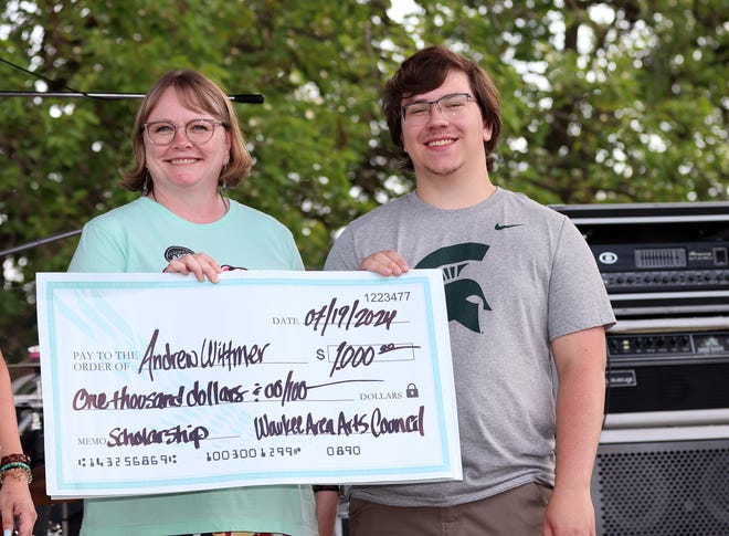 Teacher Lori Dale presents a $1,000 scholarship check to senior Andrew Wittmer during the Waukee Arts Festival on Saturday, July 20. The two-day festival at Centennial Park featured local artists and live music.