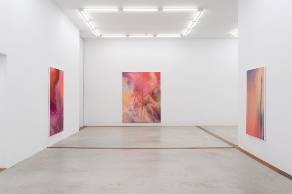 Photo of a white cube room with pink abstract paintings. 