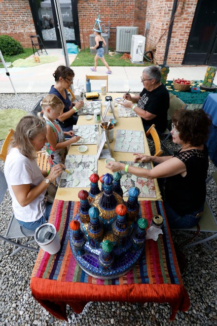 Local artist Krysia Ara top left works with locals to glaze ginkgo leaves that will used in her mosaics at FoxSaid Festival at the Cotton Press in Athens, Ga., on Saturday, July 27, 2024. The art and music festival featured interactive art with a number of local artists and raised money for art education in local schools.