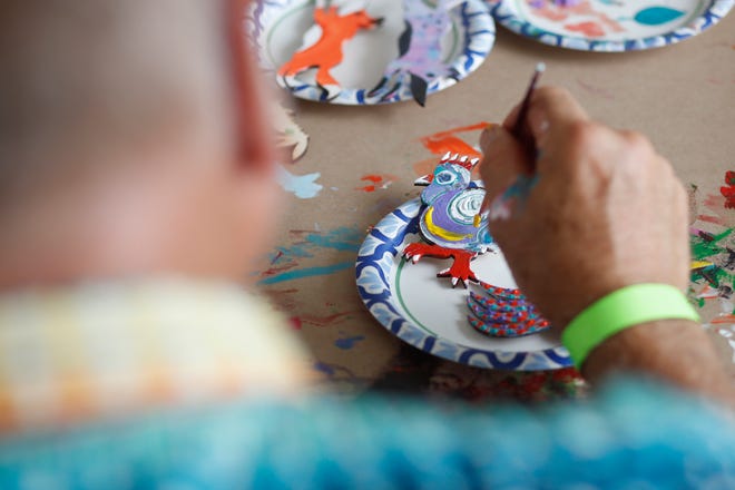 Locals paint checkers and foxes cut out by local artist Tex Crawford at FoxSaid Festival at the Cotton Press in Athens, Ga., on Saturday, July 27, 2024. The art and music festival featured interactive art with a number of local artists and raised money for art education in local schools.