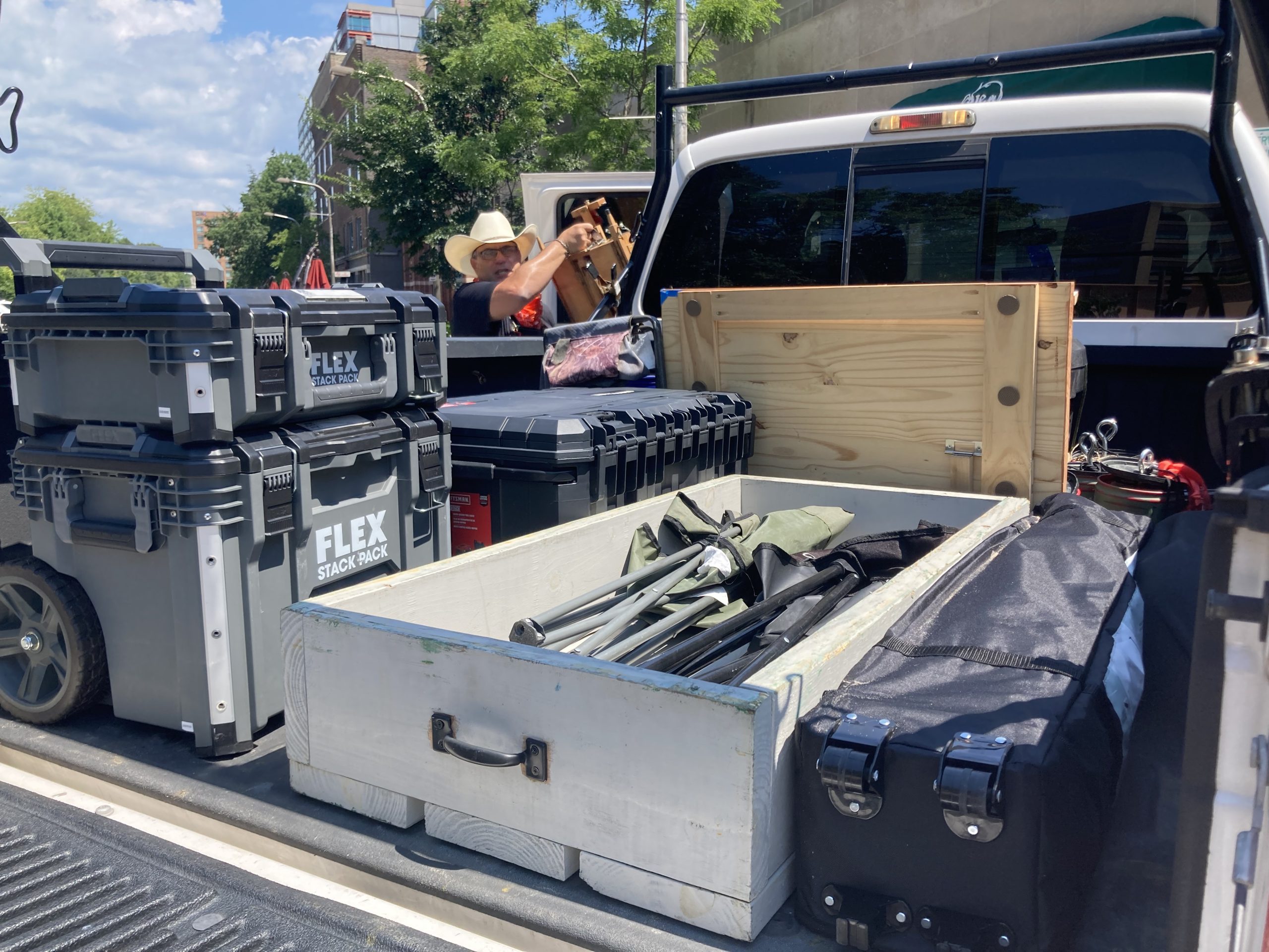 packed back of pickup truck,  man in cowboy hat unloading something in background 