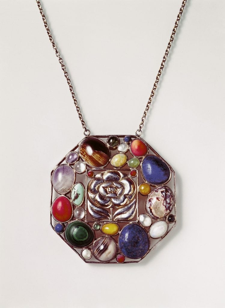 A silver pendant studded with semi-precious stones of many colors