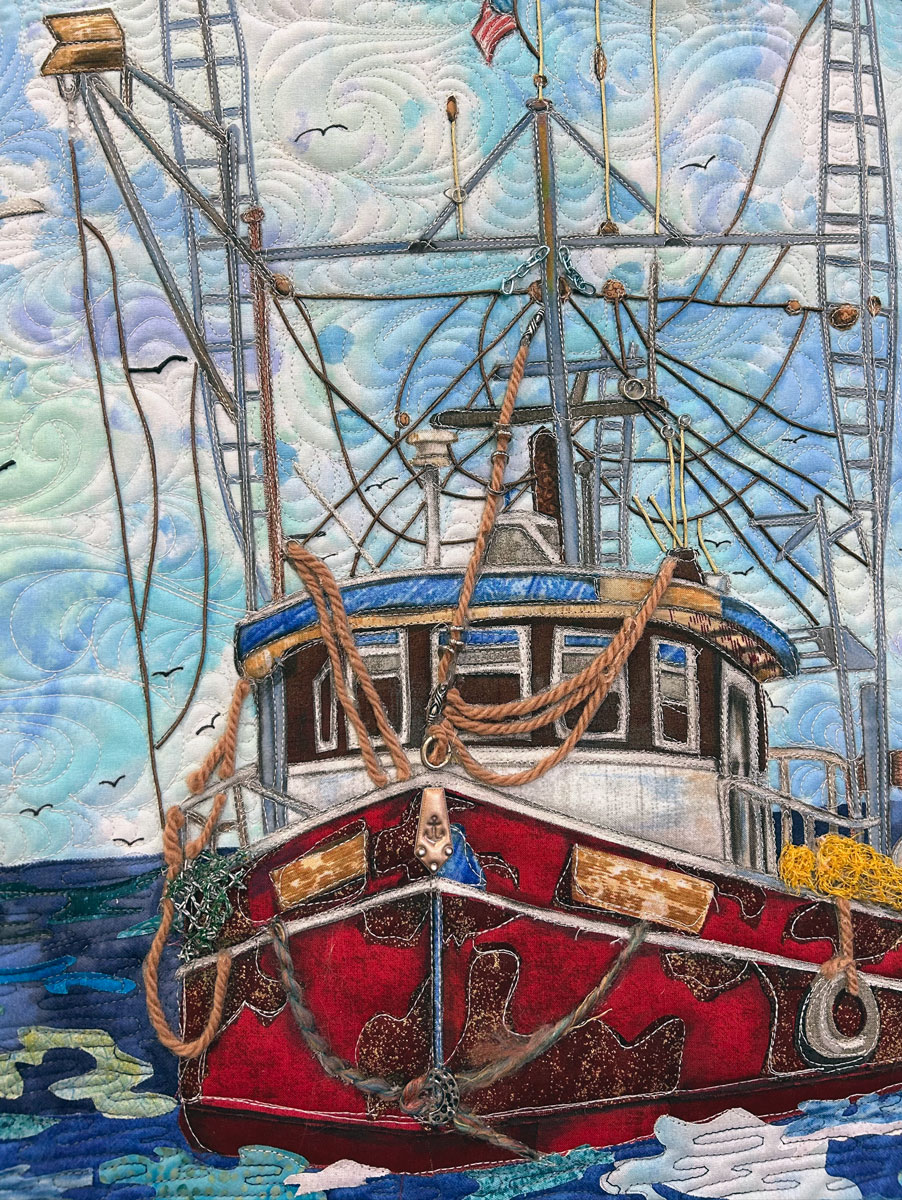 A quilted art piece depicting a red shrimping boat in the water