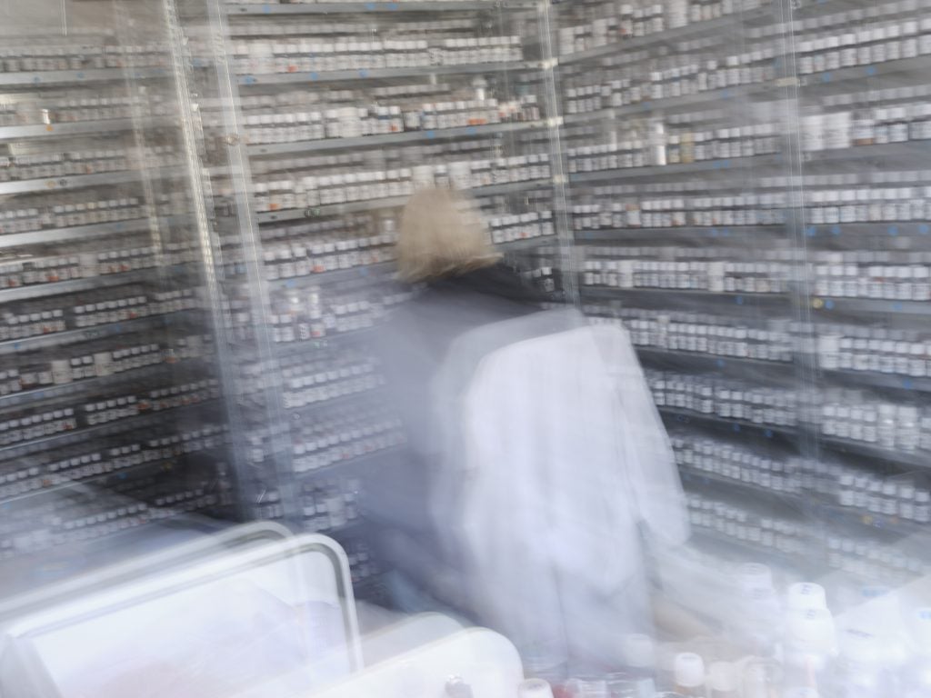 a blurry shot of a scientist in a lab with a lot of vials 