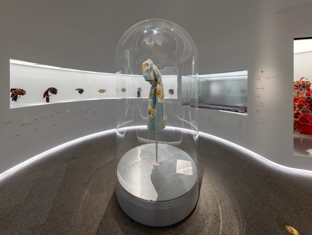 a museum has fashion garments in intricate science lab-based display cases 