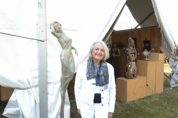 Moana Ponder, a 16-year participant in Sculpture in the Park, stands next to one of her nine sculptures she displayed at Saturday's duration of the 40th annual Sculpture in the Park show. (Riley Laub / Loveland Reporter-Herald)