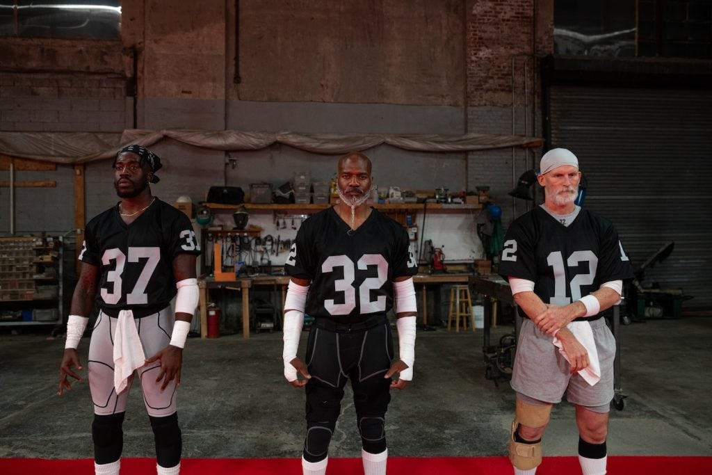 three men stand in football attire