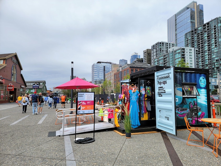 caption: Tables, chairs, and extra umbrellas outside the temporary shops on Seattle's waterfront on Tuesday, Aug. 13, 2024.
