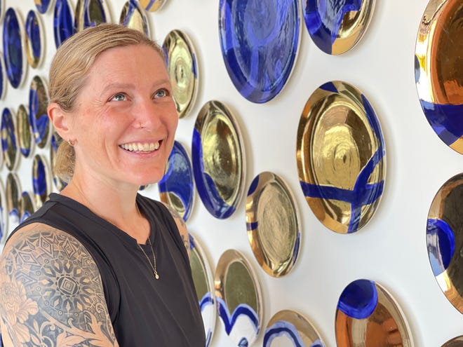 Artist Molly Hatch and her on the wall of ceramic plates.