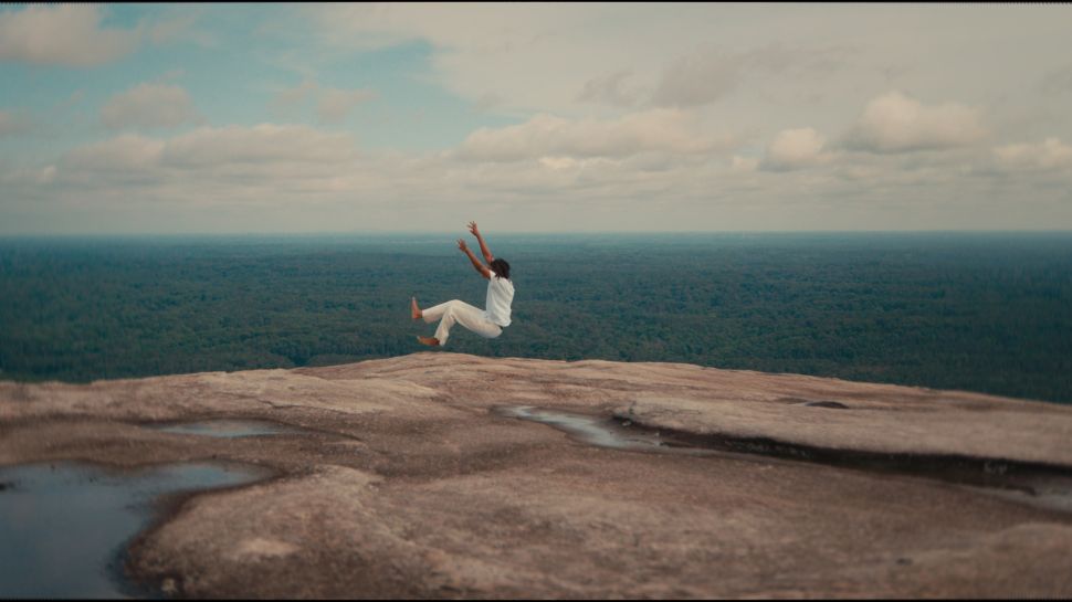 Image of a woman suspended in rocks facing the sea