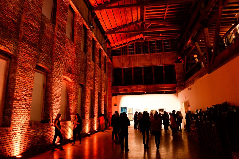 Image of a red-lightened industrial space with people gathering