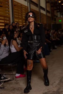 A model wears a leather outfit with oversized sunglasses.