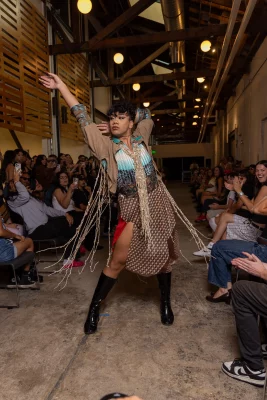 A model poses dramatically wearing a brown fringe jacket.