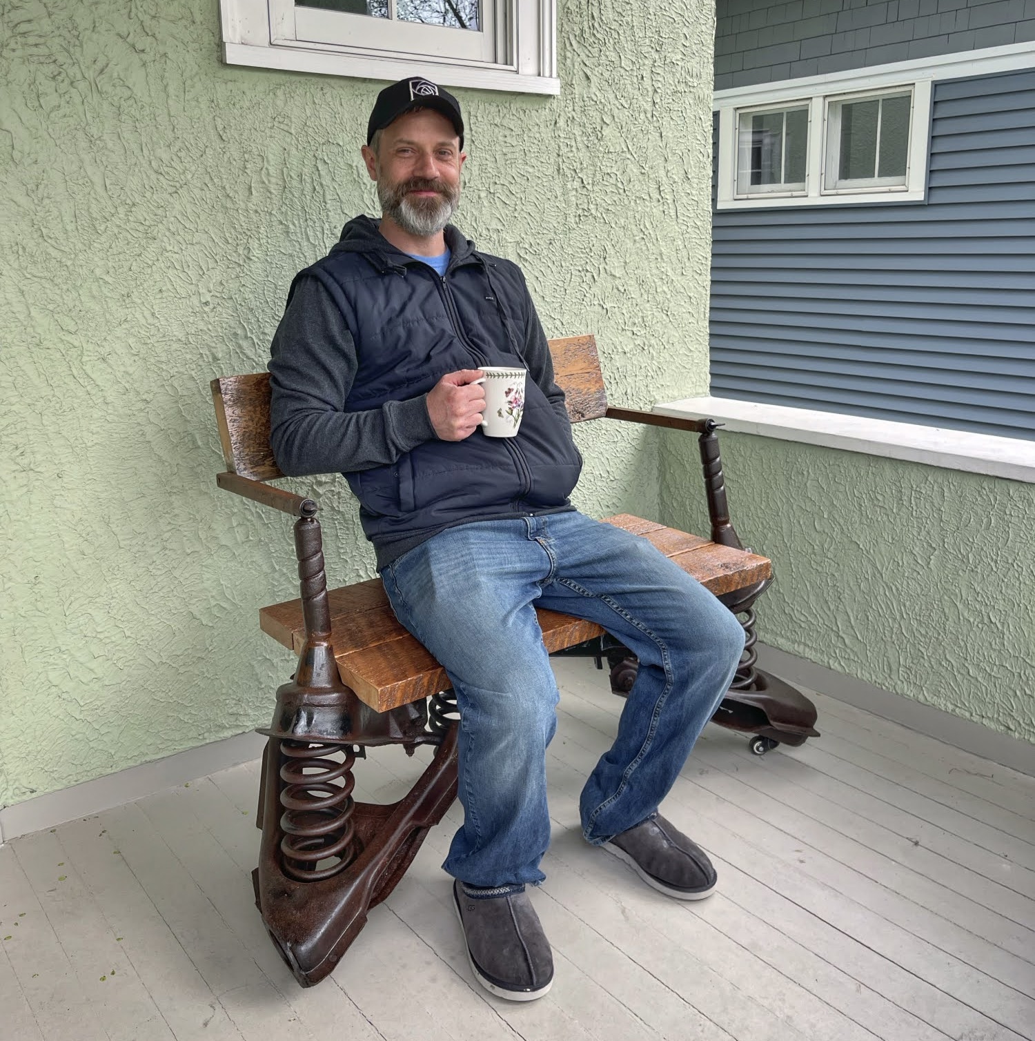 Workman holding coffee cup sitting on odd bench on porch