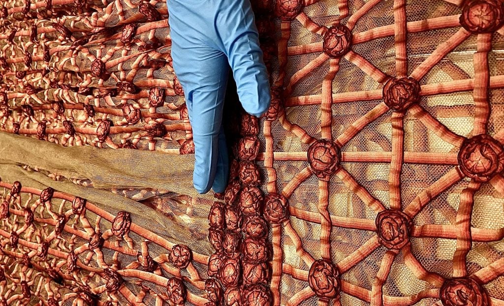 a gloved hand inspects an archival house of Lanvin dress