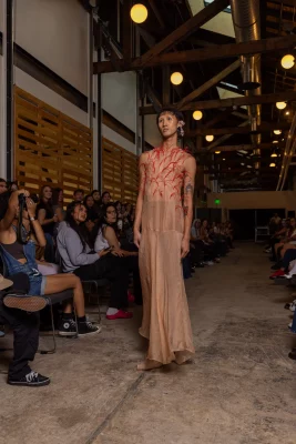 A model wears a red and nude mesh dress by Trung Q. Tham.