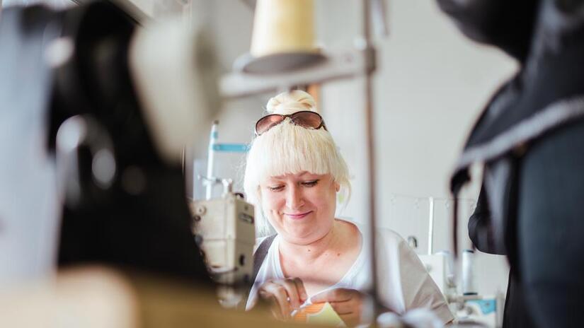 Surrounded by sewing machines, a woman from Ukraine uses needle and thread to finish a project during an art therapy programme organized by the Portuguese Red Cross.